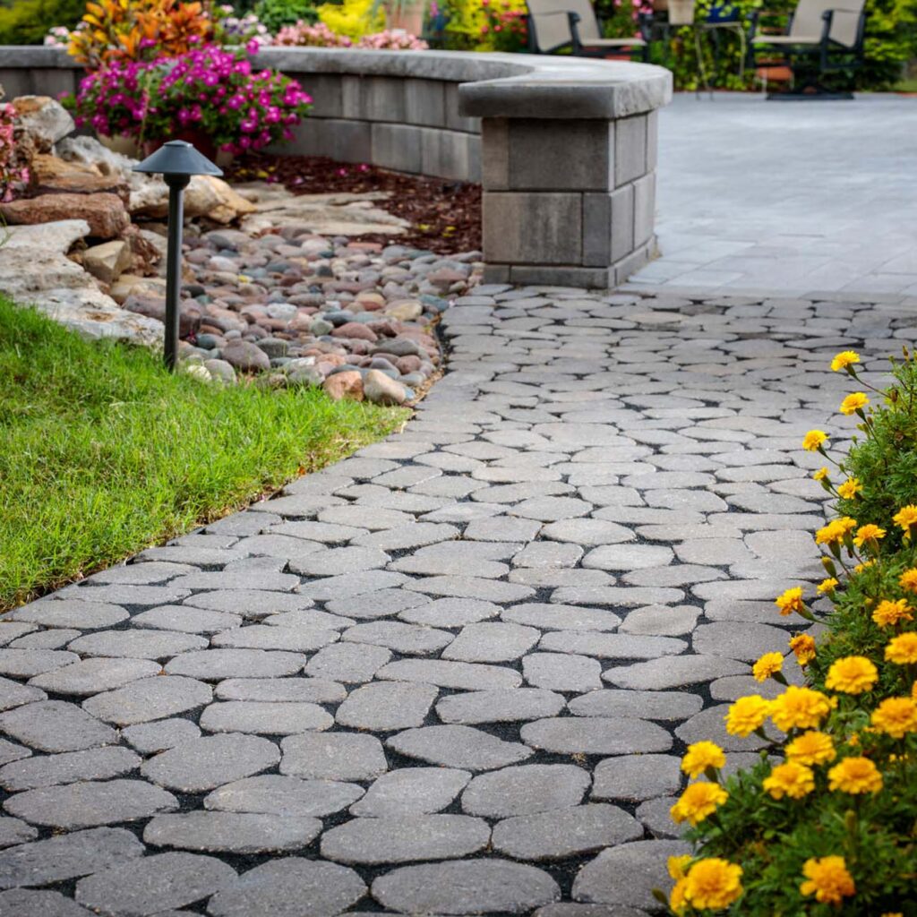 Cobblestone paver walkway leading through a landscaped yard